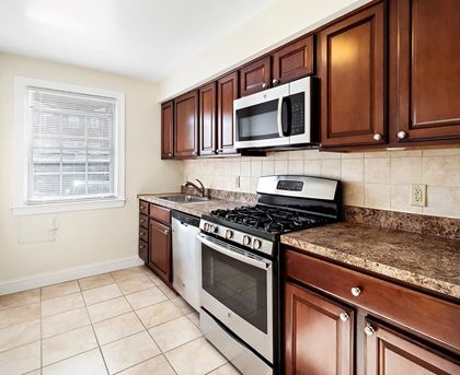 a kitchen with a stove and microwave and wooden cabinets